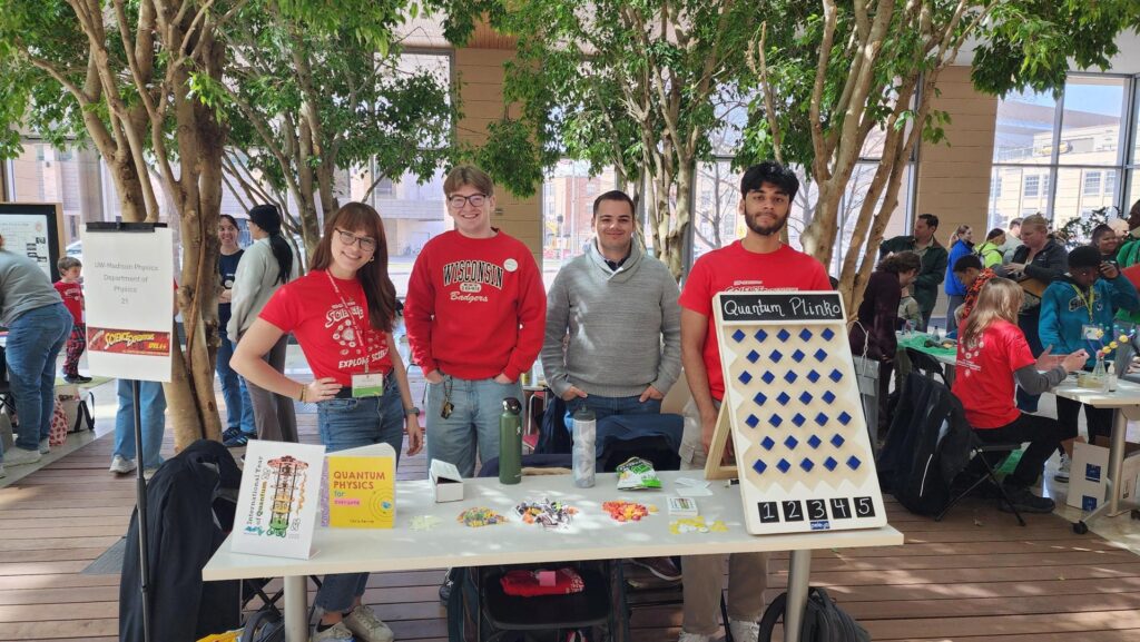 four people stand behind a table that contains physics demos