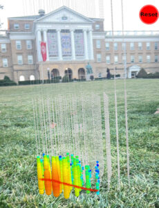 a rainbow array of dots shows the track of detection in the Icecube detector, but since it's shown on an app on a phone screen, the array is positioned in front of Bascom Hall