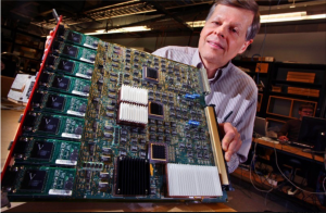 Wesley Smith holds a large electronics board full of circuits and wires