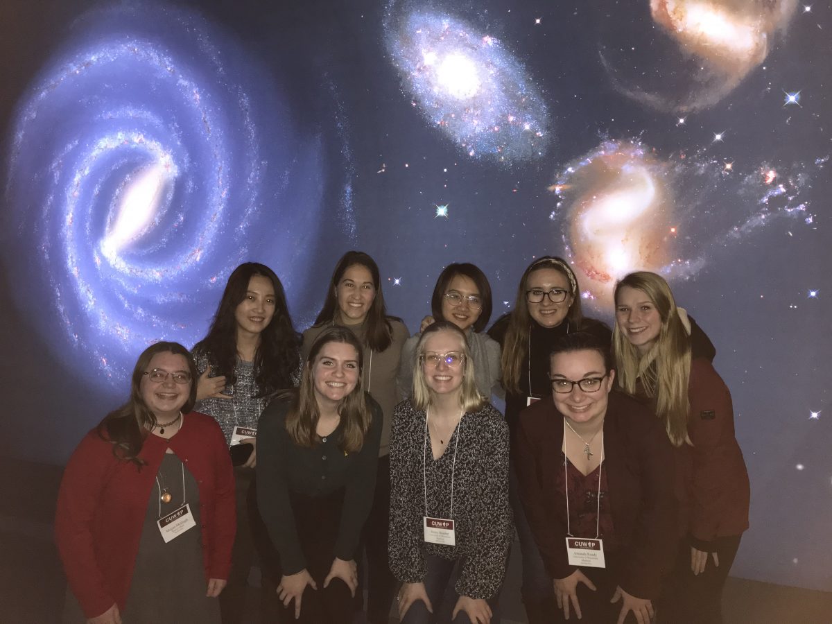 group photo in front of an astronomy and galaxy-themed backdrop