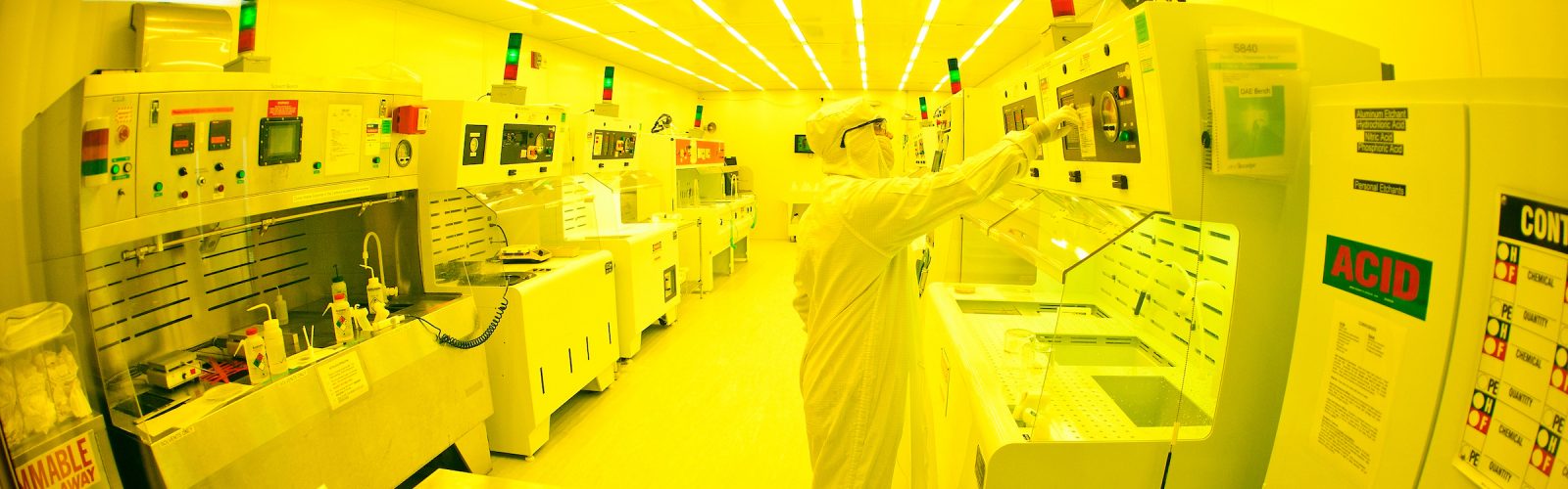 a very yellow-hued image of a person in a full-body clean suit working in a clean room