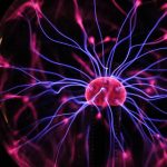 a plasma ball shows neon-like strands filling a sphere against a pitch-black background