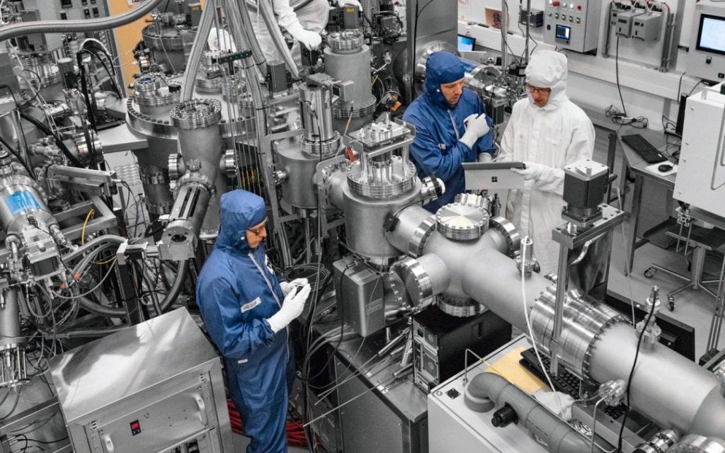 people in blue clean suits in a computer / electronics room