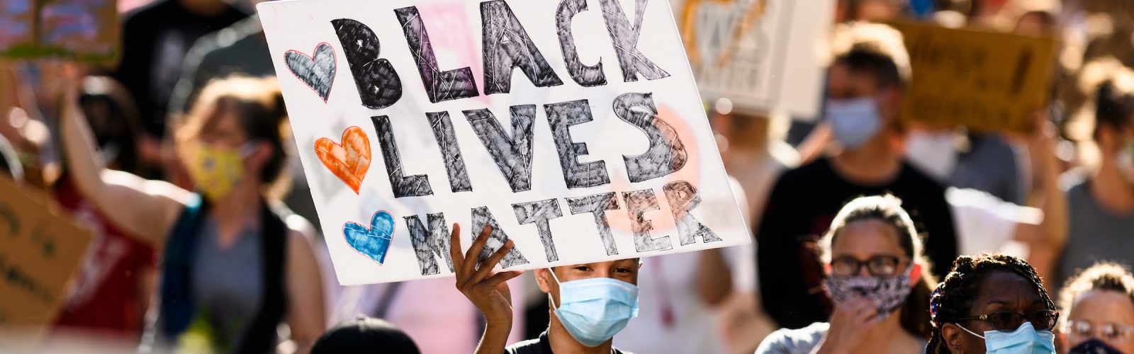 a sign that says "black lives matter" is held up in a crowd of many other people and signs