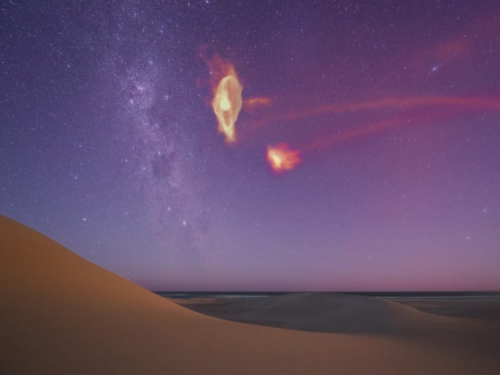 a starscape showing the milky way in the distance and a rendering of the gases surrounding the large magellenic cloud