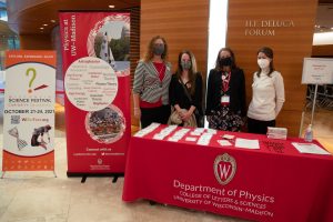 four people stand behind a table that says 'department of physics'