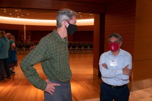 two men talking with the lecture hall in the background