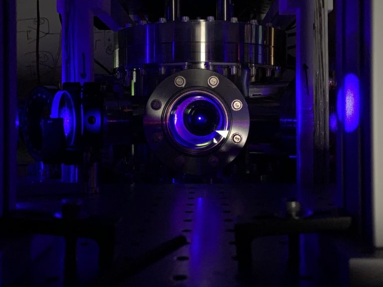 a metal apparatus with a focused blue laser dot in the center made up of fluorescent atoms