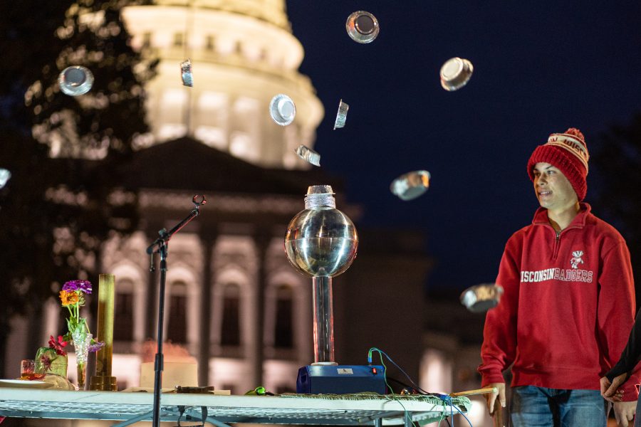 a man in front of an illuminated state capitol with pie plates "floating" around him