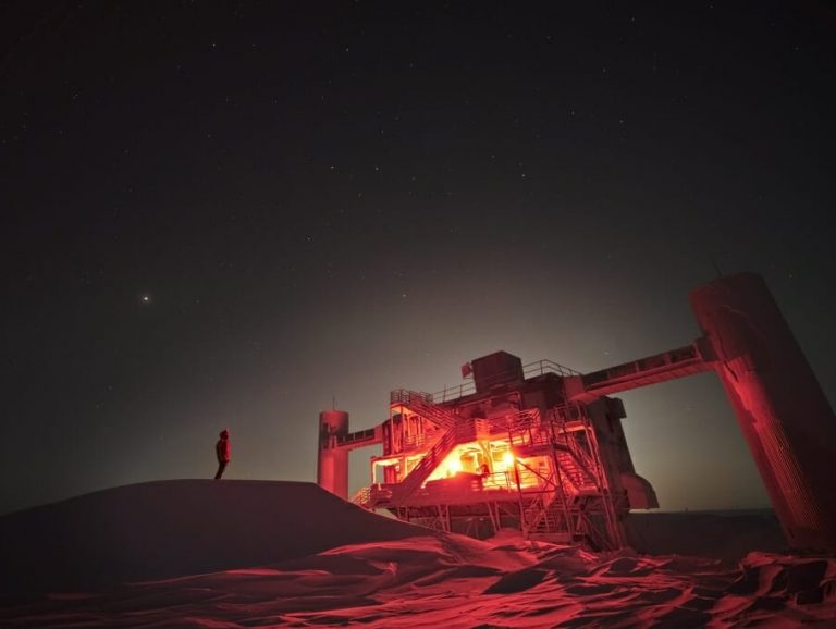 illuminated IceCube observatory with the night sky behind it