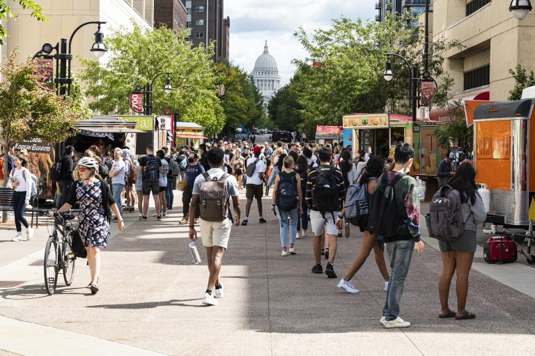 Students and pedestrians walk among the food carts on Library Mall during the first morning of classes for the Fall semester on Sept. 8, 2021. A campus health mandate requires people to wear face mask indoors – except while eating or drinking – as the coronavirus (COVID-19) pandemic continues. Face coverings are not required while outdoors. (Photo by Bryce Richter / UW-Madison)