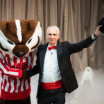 bucky badger, the mascot, shakes hands with a man in a tuxedo