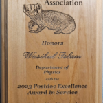 a wood plaque that says UW Postdoc Association, has a carved out badger, and says Wasikul Islam, department of physics, 2023 Postdoc excellence award in service,