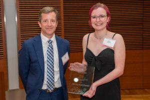 a man on the left with a woman on the right holding a clear glass plaque