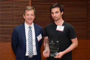 a man on the left with a man on the right holding a clear glass plaque