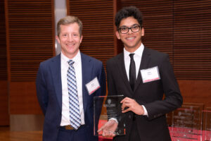 a man on the left with a man on the right holding a clear glass plaque