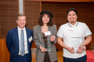 a man on the left with a woman in the middle holding a clear glass plaque and a man on the right holding a clear glass plaque