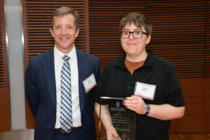 a man on the left with a person on the right holding a clear glass plaque