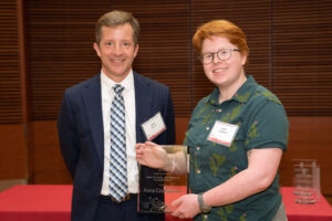 a man on the left with a woman on the right holding a clear glass plaque