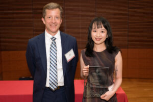 a man on the left with a woman on the right holding a clear glass plaque