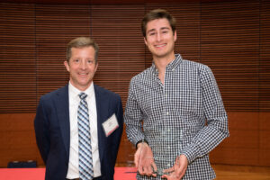 a man on the left with a man on the right holding a clear glass plaque