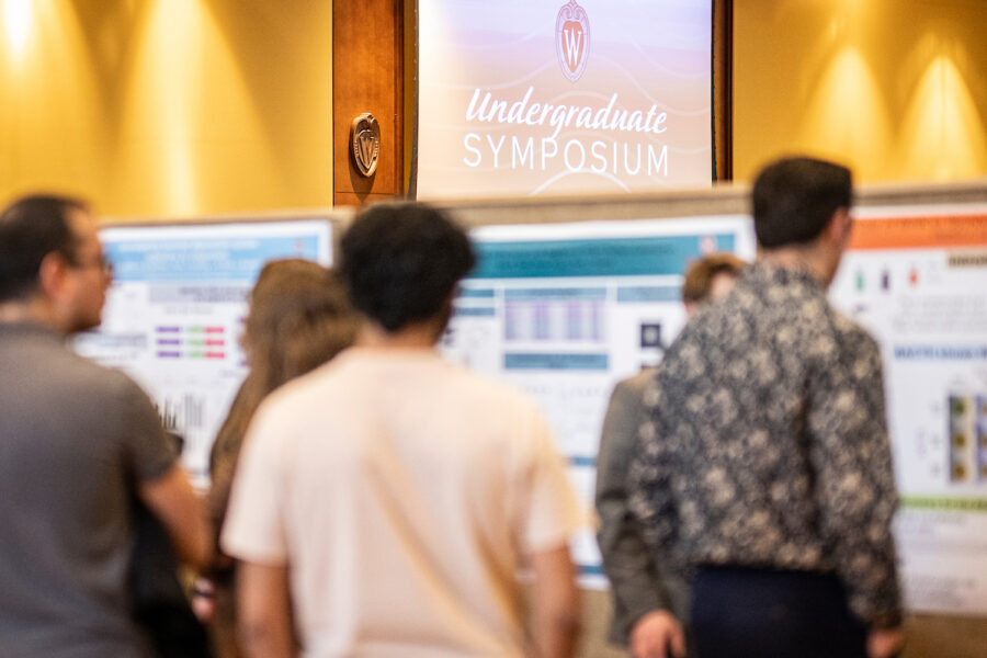 the focus of this image is on the background, with research posters tacked to boards and a sign above that says 