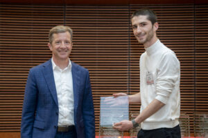 two men stand next to each other, one is holding a glass plaque