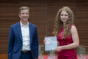 a woman holds a glass plaque, she is standing next to a man