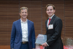 two men stand next to each other, one is holding a glass plaque