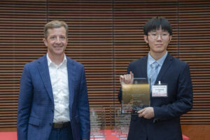 two men stand next to each other, one is holding a glass plaque