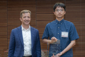 two men stand next to each other, one is holding a glass plaque