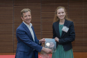 a man and woman both hold a glass plaque and are smiling