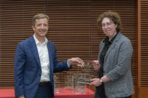 two people stand next to each other and smile, they are both holding and showing off a glass plaque