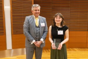 two people stand, one is holding a glass plaque