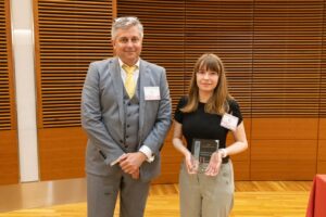 two people stand, one is holding a glass plaque