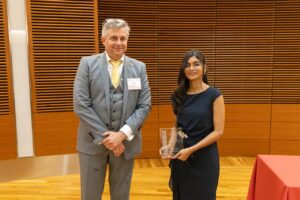 two people stand, one is holding a glass plaque