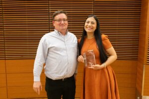 two people stand, one has a glass plaque