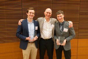 three men pose ,two have plaques