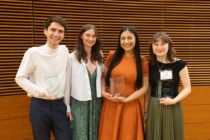 four people pose, three have plaques