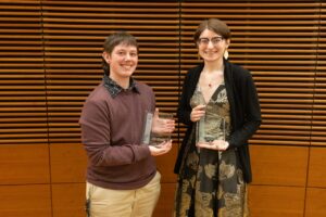 two students stand with glass plaques