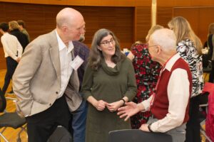 three people stand and talk after an academic ceremony