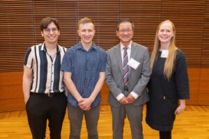 four people stand and smile for the camera