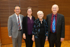four people stand and smile at the camera