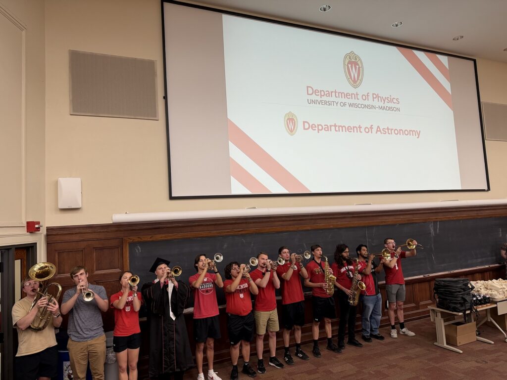 a dozen or so students play band instruments at the front of a lecture hall