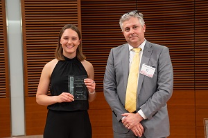 two people stand, one is holding a glass plaque