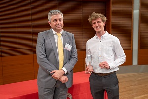 two people stand, one is holding a glass plaque