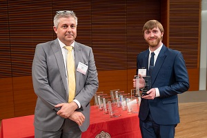 two people stand, one is holding a glass plaque