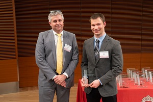 two people stand, one is holding a glass plaque