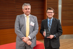 two people stand, one is holding a glass plaque