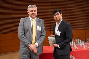 two people stand, one is holding a glass plaque